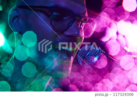 Close-up photo of singer's face, bathed in colorful stage lights, captures electric energy and emotion of moment. Close-up photo of singer's face, bathed in colorful stage lights, captures electric energy and emotion of moment. 117329306