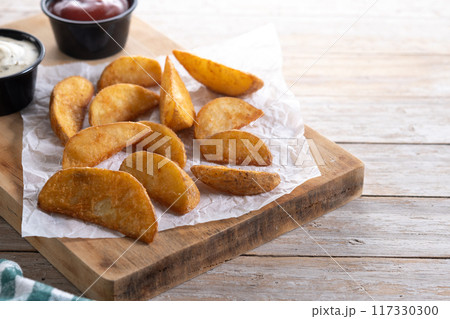 Fried potato wedges wooden table. Copy space 117330300