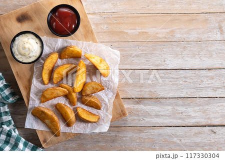 Fried potato wedges wooden table. Top view. Copy space 117330304