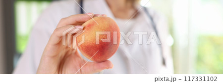 Doctor nutritionist holding ripe peach in hand Doctor nutritionist holding ripe peach in hand 117331102