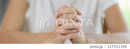 Woman sitting at table and putting hands in lock on book Woman sitting at table and putting hands in lock on book 117331109