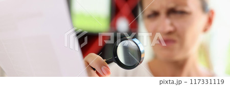 Woman trying read papers with magnifier glass, squinting to see more clearly 117331119