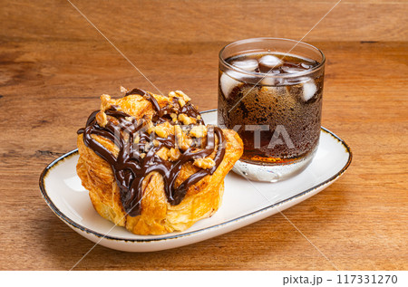 High angle view of chocolate butter bun and a glass of ice cola water. 117331270