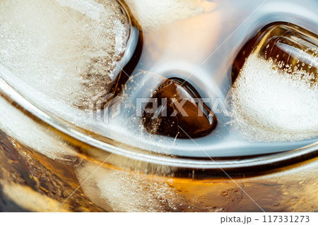 High angle view of ice cubes floating in aerated cola water. High angle view of ice cubes floating in aerated cola water. 117331273