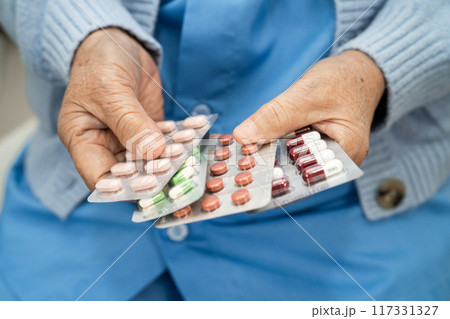 Asian senior woman patient holding antibiotics capsule pills  for treatment infection patient in hospital, Pharmacy drugstore concept. 117331327