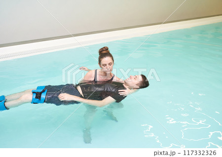 Two people in pool. Watsu man. Blue water rehabilitation massage. Aqua therapy 117332326
