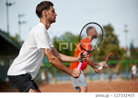 Focus on concentrated man in white t-shirt showing focus readiness for intense outdoor game with his friend. Competitive spirit. Focus on concentrated man in white t-shirt showing focus readiness for intense outdoor game with his friend. Competitive spirit. 117332455