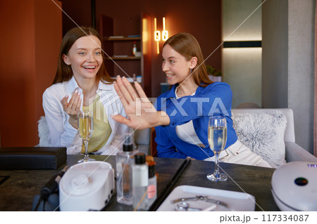 Two happy satisfied female clients after manicure at nail studio Two happy satisfied female clients after manicure at nail studio 117334087