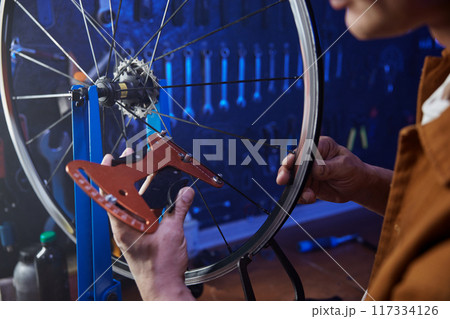 Bike mechanic doing tensioning and alignment of bicycle spokes closeup view Bike mechanic doing tensioning and alignment of bicycle spokes closeup view 117334126