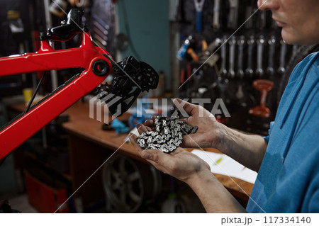 Male master holding new chain getting ready to repair bicycle Male master holding new chain getting ready to repair bicycle 117334140