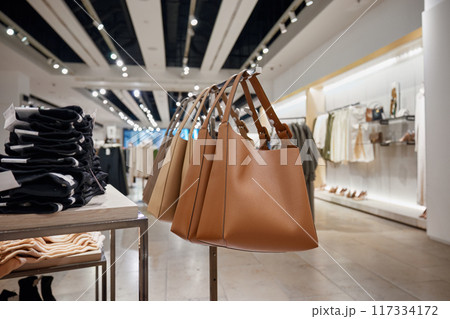 Luxury leather handbag hanging on rack in shop boutique display Luxury leather handbag hanging on rack in shop boutique display 117334172