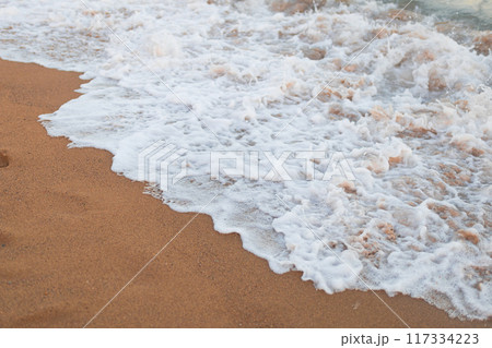 Soft ocean wave on clean sandy beach background. 117334223