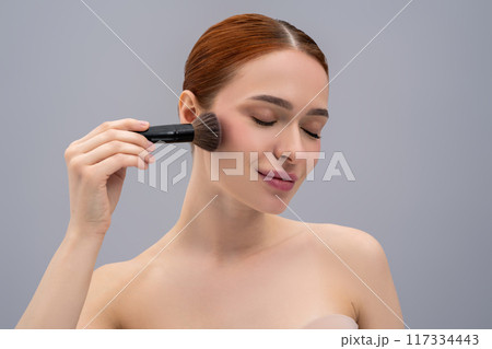 Young pretty woman doing make up and using face brush Young pretty woman doing make up and using face brush 117334443