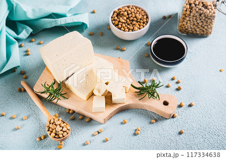 Organic vegetarian soy tofu and rosemary on wooden board on table Organic vegetarian soy tofu and rosemary on wooden board on table 117334638