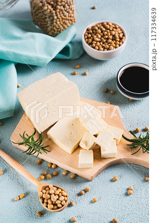 Organic vegetarian soy tofu and rosemary on wooden board on table vertical view Organic vegetarian soy tofu and rosemary on wooden board on table vertical view 117334639