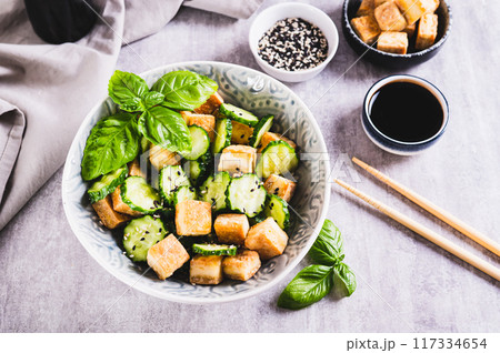 Vegetarian salad with fried tofu and fresh cucumbers in a bowl on the table Vegetarian salad with fried tofu and fresh cucumbers in a bowl on the table 117334654