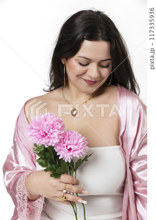 Curvy girl posing with a white dress and some flowers in her hand 117335936