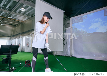 室内ゴルフ練習場で練習をする女性 117336717