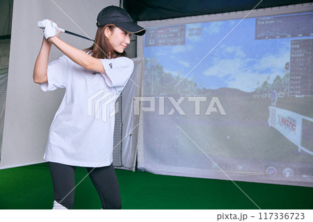 室内ゴルフ練習場で練習をする女性 117336723