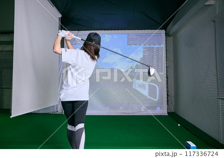 室内ゴルフ練習場で練習をする女性 117336724