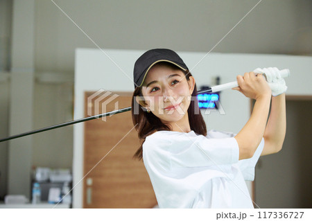 室内ゴルフ練習場で練習をする女性 117336727