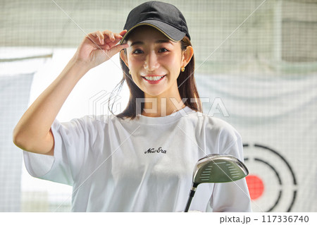 室内ゴルフ練習場で練習をする女性 117336740