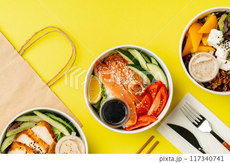 Top view of fresh poke bowls on yellow background 117340741