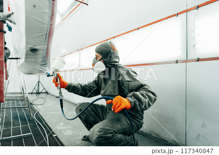 Auto painter painting a car with vaporizer gun inside a paint booth Auto painter painting a car with vaporizer gun inside a paint booth 117340847