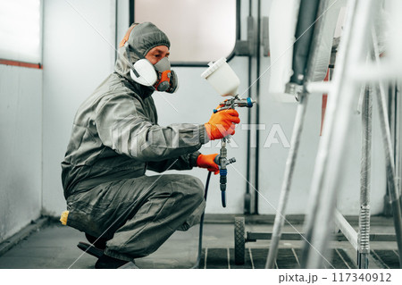 Auto painter painting a car with vaporizer gun inside a paint booth 117340912