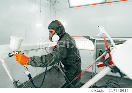 Auto painter painting a car with vaporizer gun inside a paint booth 117340913