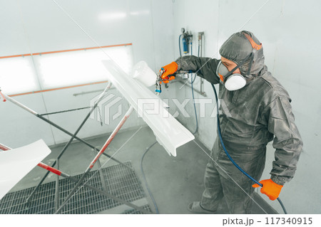 Auto painter painting a car with vaporizer gun inside a paint booth 117340915