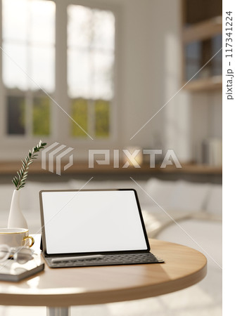 A digital tablet mockup on a round wooden table in a comfortable, contemporary living room. 117341224