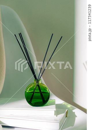 Liquid home perfume in glass diffuser with sticks on chair Liquid home perfume in glass diffuser with sticks on chair 117341239
