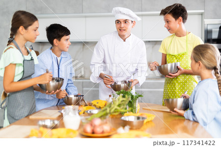 In cooking class, guy cook with bowl in hands tells children participants culinary ticks and tricks 117341422