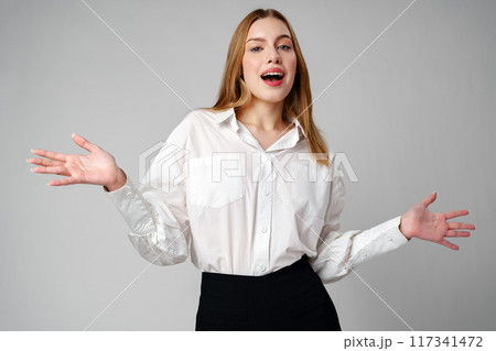 Joyful Young Blonde Woman Smiling against gray background 117341472