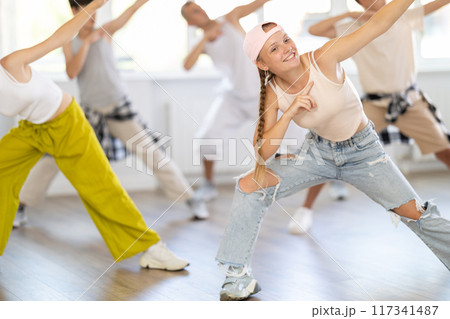 Girl in baseball cap with two hair pigtails with group of teenage friends, learn to dance hip hop Girl in baseball cap with two hair pigtails with group of teenage friends, learn to dance hip hop 117341487