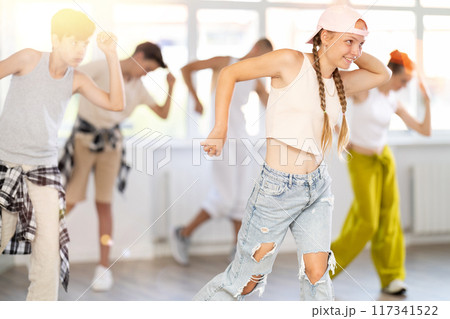 Teenage girl practicing hip hop slide moves in training hall Teenage girl practicing hip hop slide moves in training hall 117341522
