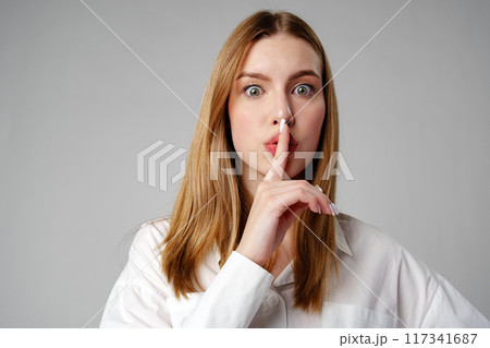 Young Woman Making a Hush Gesture on gray background 117341687