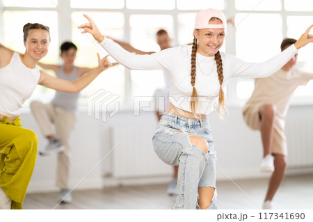 Teenage girl practicing hip hop reject step in training hall Teenage girl practicing hip hop reject step in training hall 117341690