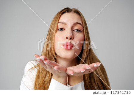 Young Woman Blowing a Kiss Towards the Camera in a Studio 117341736