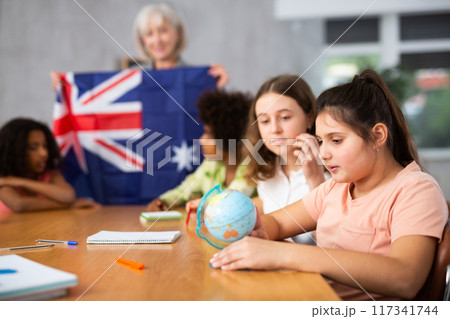 Female teacher showing australian flag to kids in geography class Female teacher showing australian flag to kids in geography class 117341744