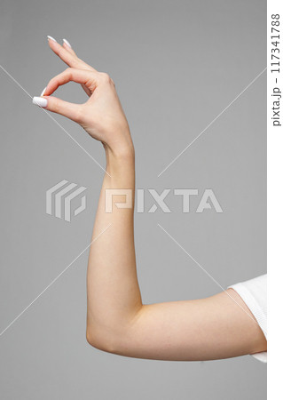Female hand gesturing sign against gray background Female hand gesturing sign against gray background 117341788