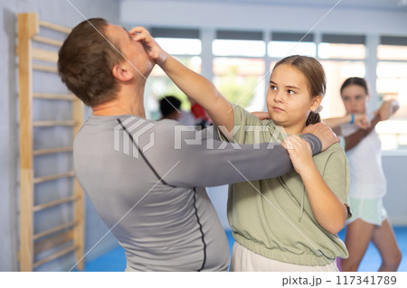 Tween girl attacking eyes of coach during sparring at self-defense training Tween girl attacking eyes of coach during sparring at self-defense training 117341789