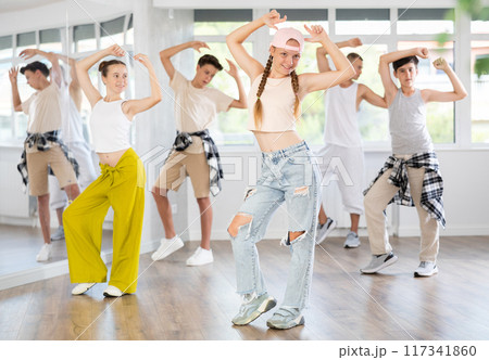 Teenage girl practicing basic hip hop moves in training hall Teenage girl practicing basic hip hop moves in training hall 117341860