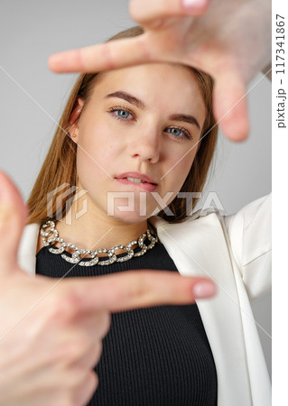 Young Woman Making Frame Gesture With Hands Against a Neutral Background 117341867