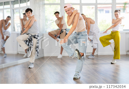 Girl in baseball cap with two hair pigtails with group of teenage friends, learn to dance hip hop 117342034