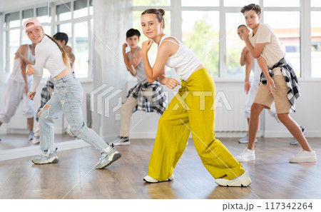 Teenagers in casual clothes are training together to dance hip-hop and breakdancing in dance center Teenagers in casual clothes are training together to dance hip-hop and breakdancing in dance center 117342264