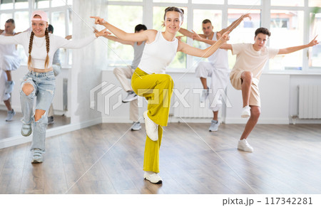 Teenage girl practicing hip hop reject step in training hall 117342281
