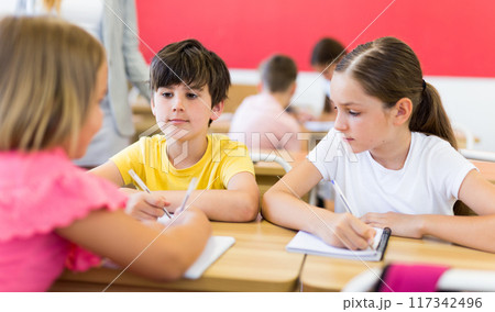 Concentrated preteen girls and boys solving teacher assignments in groups Concentrated preteen girls and boys solving teacher assignments in groups 117342496