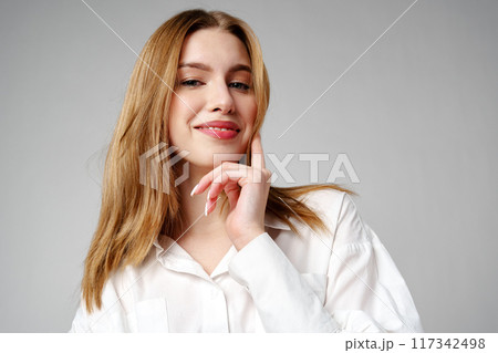 Joyful Young Blonde Woman Smiling against gray background 117342498